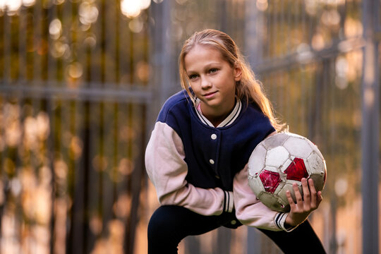 girl is holding a soccer ball on a soccer field in the yard.
