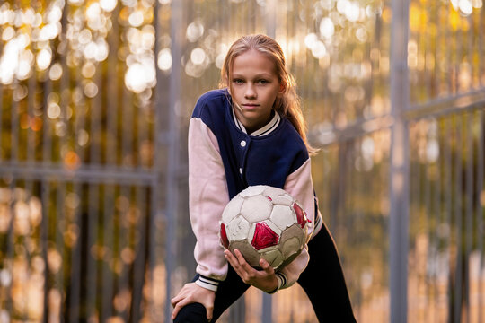 girl is holding a soccer ball on a soccer field in the yard.