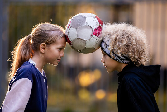 Girl and boy balancing a soccer ball with their heads