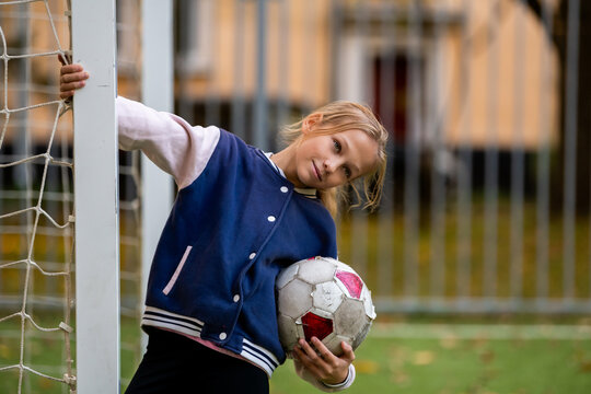 girl is holding a soccer ball on a soccer field in the yard.