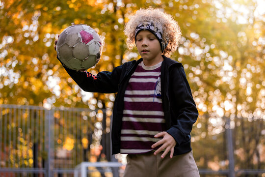 Young boy playing soccer on an outdoor field during sunset.