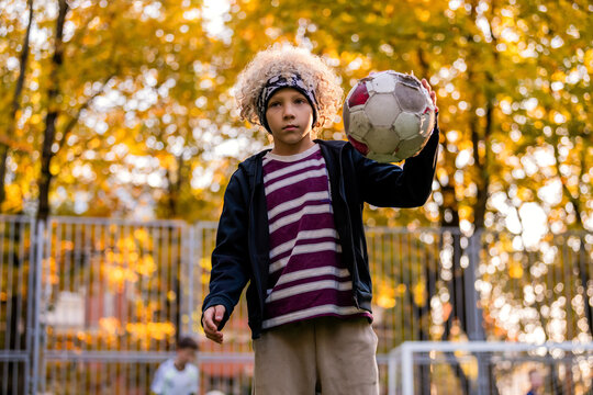 Young boy playing soccer on an outdoor field during sunset.