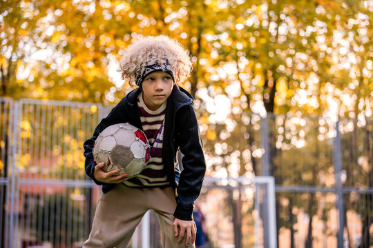 Young boy playing soccer on an outdoor field during sunset.