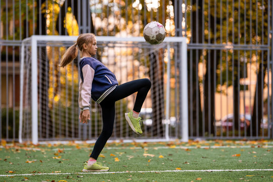 girl jongling soccer ball on field at autumn day.