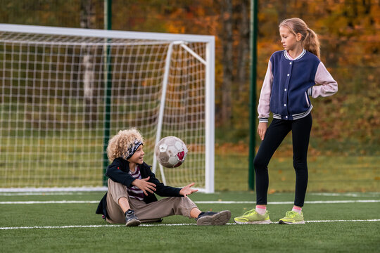 boy with a ball and a girl are talking on a football field.