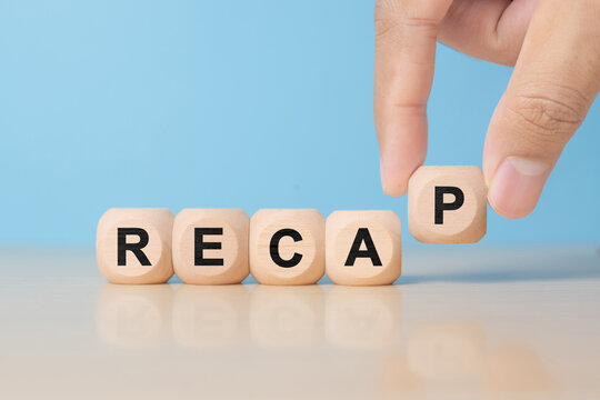 recap sign made of blocks on a table with a reflective surface, blue background