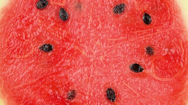Macro texture of rotating fresh watermelon flesh. Red fruit pulp background with seeds.