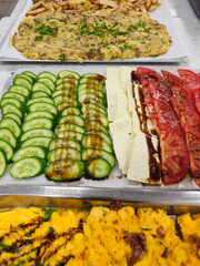 Breakfast buffet offering scrambled eggs and fresh vegetables