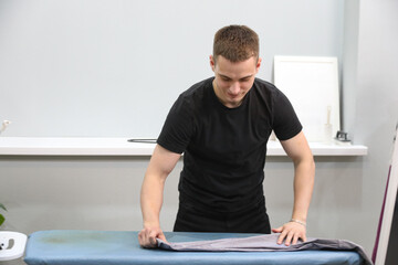 Fototapeta premium Young man ironing his clothes at home