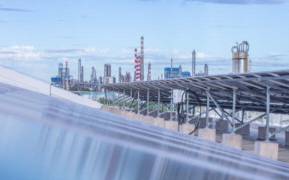 A high-tech photovoltaic control panel with digital interfaces and indicator lights, set against a background of sprawling industrial pipelines and storage tanks, creating a bold contrast between