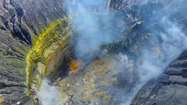 The crater of the volcano on Mount Bromo is located inside the Tengger caldera. Sulfurous fumes rise into the air on the island of Java, an active volcano in Indonesia, as seen from a bird's-eye view.