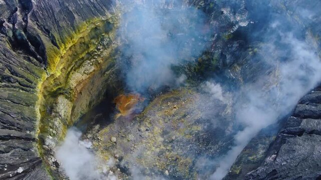 The crater of the volcano on Mount Bromo is located inside the Tengger caldera. Sulfurous fumes rise into the air on the island of Java, an active volcano in Indonesia, as seen from a bird's-eye view.