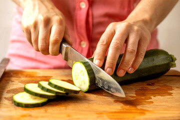 Close-Up of Hands Slicing Fresh Zucchini on Wooden Cutting Board for Healthy Home Cooking