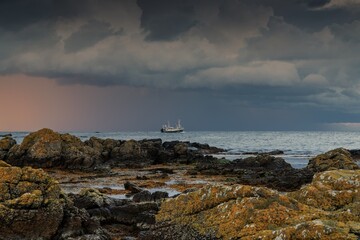 view of the scenic Bornholm coast at Fyrnakken i Svaneke at sunset with a fishing boat speedily passing by