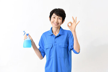清掃用スプレーを持ちOKサインをする作業服のアジア人の中高年女性