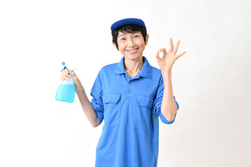 清掃用スプレーを持ちOKサインをする作業服のアジア人の中高年女性