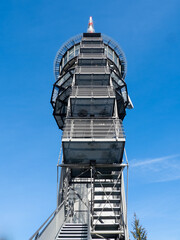 Obraz premium Modern steel observation tower with exterior staircase and antenna against a clear blue sky