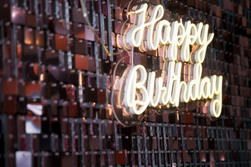 A birthday sign with LED lights illuminating a glossy background.