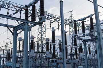 Industrial electrical substation with high voltage equipment and steel structures during sunset. Power infrastructure for energy distribution, electricity supply industry and engineering technology.