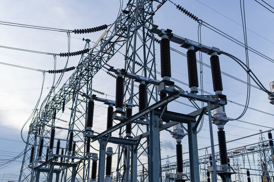 Low angle view of high voltage electrical isolators and circuit breaker components on a steel structure at a power substation. Industrial infrastructure for electricity distribution and energy grid ma