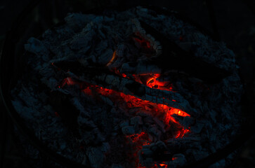 Glowing Embers in Cold Night Ashes Create Warm Light and Subtle Fire Spots in a Fire Pit