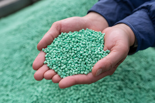Human hands delicately hold vibrant green plastic pellets, showcasing uniform granules used in industrial manufacturing processes, emphasizing raw material quality and sustainable supply.
