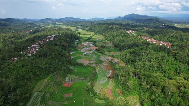 Aerial drone footage on top of a green vegetable valley in a volcanic area in java island Indonesia, with forests and local villages around