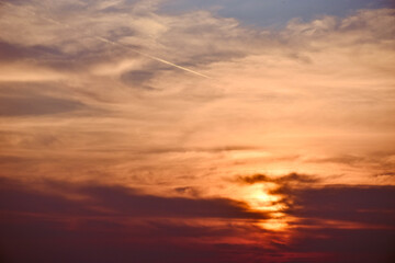 Fototapeta premium Sunlight filters through the haze, while a jet carves its path through the golden hour.