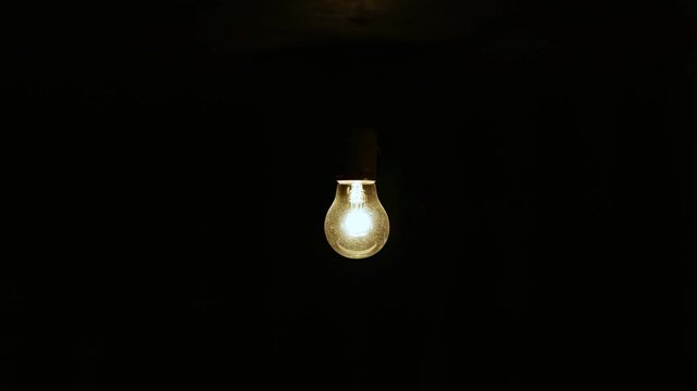 Light bulb illumination sequence: from darkness to bright glow in minimalist setting