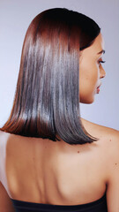 Naklejka premium A profile of a brunette fashion model with long straight brown hair and glamour makeup posing in a studio for beauty and skin care