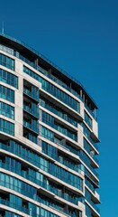 Fototapeta premium A striking image of a contemporary high-rise apartment complex featuring glass facades and angular concrete elements against a clear blue sky, exterior, condominium, abstraction