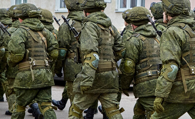 Fototapeta premium Soldiers in military uniforms marching through urban area during daylight hours in a routine exercise