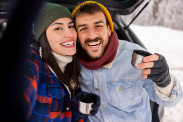 Couple having fun taking selfies while taking a winter vacation road trip break