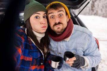 Couple having fun taking selfies while taking a winter vacation road trip break