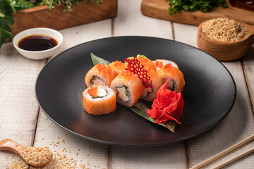 Salmon philadelphia sushi rolls with cream cheese and caviar served on a black plate with ginger wasabi and soy sauce © Hihitetlin