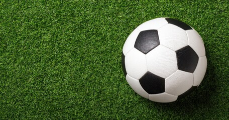 Soccer ball, classic design, resting on vibrant, green, artificial turf. Simple, clean composition