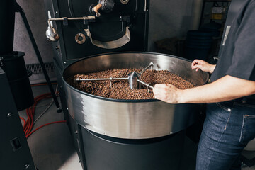 Unrecognizable employee standing at the coffee roasting machine