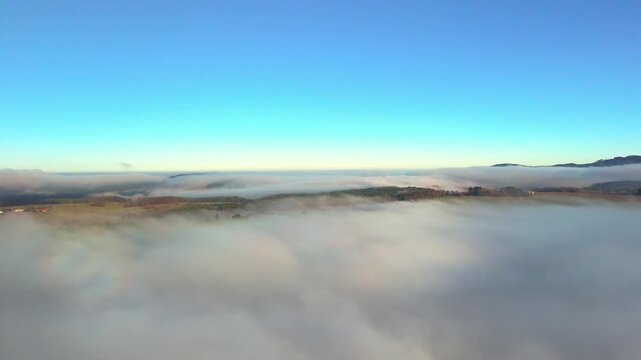 Aerial view of a sea of fog over countryside under clear blue sky