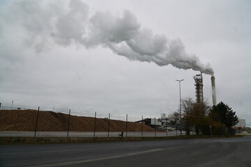 Obraz premium Smoke clouds from a sugar factory operating at full capacity in October. In the foreground, a long pile of sugar beet tubers (Beta vulgaris). Nordstemmen, Lower Saxony, Germany.