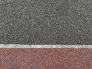 Fototapeta premium Textured dark grey and red rubber surface with white line
