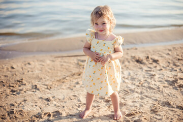 Happy little girl playing on the beach during summer vacation, enjoying outdoor fun by the tropical sea under clear blue sky.