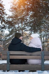 Couple Rests Warmly, Winter Embrace With Peaceful Closeness, Snowy Scene Featuring Affectionate Partners Resting Peacefully, Two Individuals Sitting Intimately On Snowy Bench Amidst Pine Trees