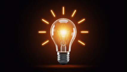 An illuminated glass light bulb glowing brightly against a dark black background represents a creative concept of energy, innovation, and a powerful electric idea for modern technology and inspiration