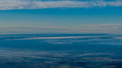 Weite Aussicht auf die Landschaft von oben bei klarem Himmel und Wolken am frühen Morgen