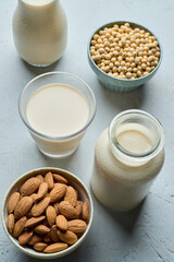 Soybean seeds and almond seeds with almond milk, soy milk on gray background.
