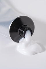 White cosmetic cream or hair product dispensing from a tube.