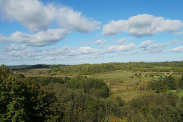 Obraz premium Forests, hills, and copses under a blue sky with beautiful clouds on a sunny summer day.