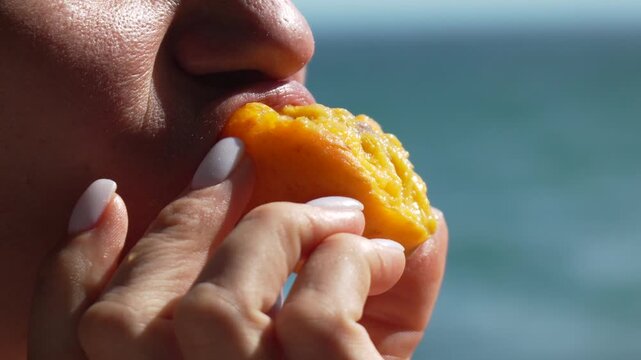 Mango beach ocean, woman eating mango on beach in daytime for refreshment.