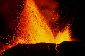 Spectacular volcanic eruption at night with bright orange and yellow lava fountains shooting skyward from crater. Generative AI