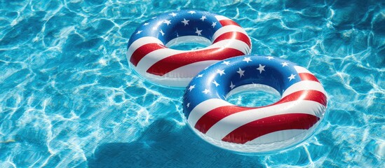 Two patriotic swim rings float on sparkling blue pool water on a sunny day
